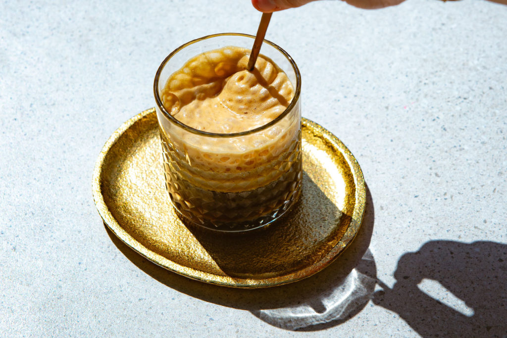 someone stirring the foam in a glass of shakerato